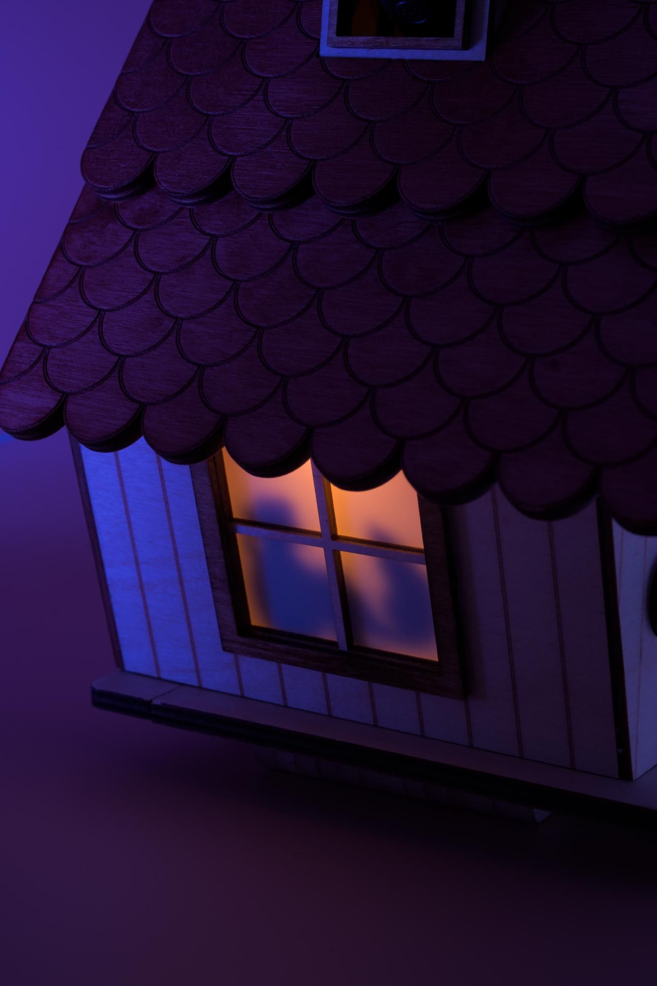 Illuminated window on the side with silhouette of girl and cat